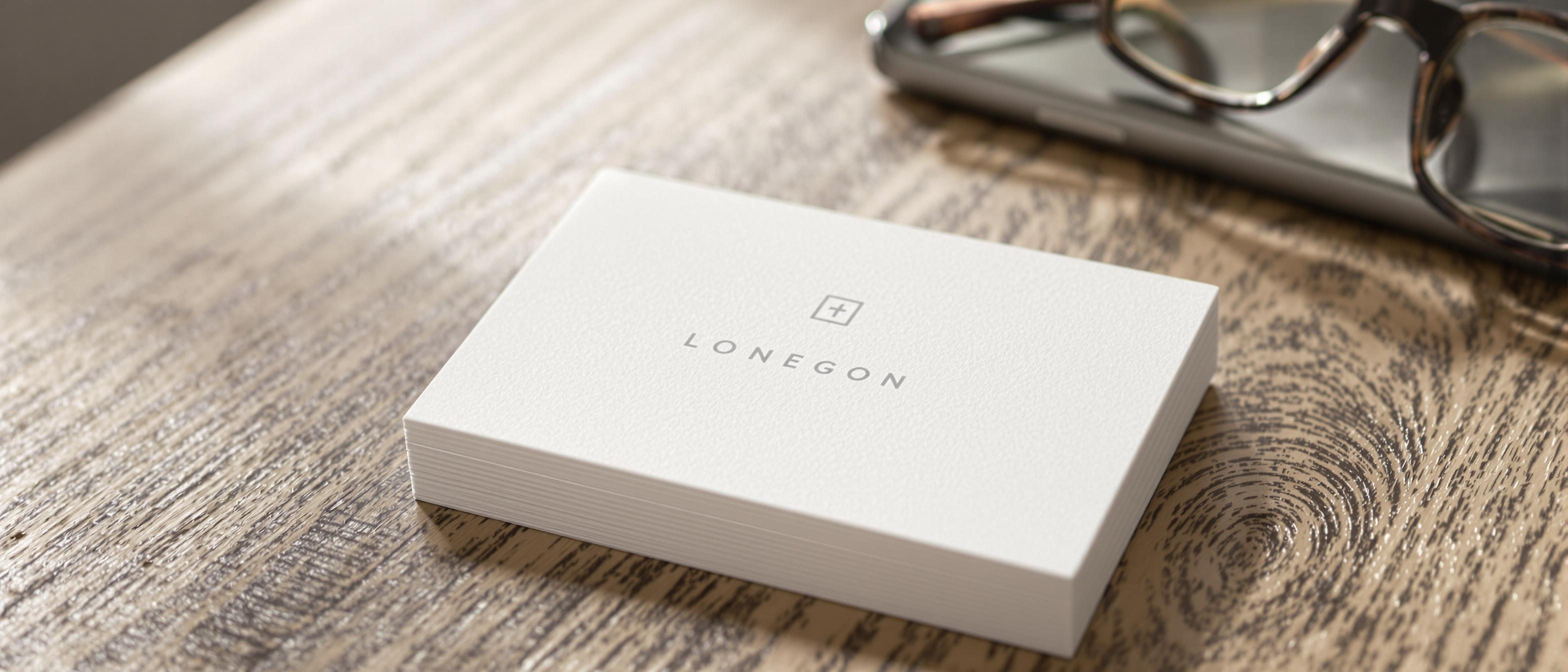 A close-up shot of a minimalist business card placed on a desk beside a smartphone and glasses.
