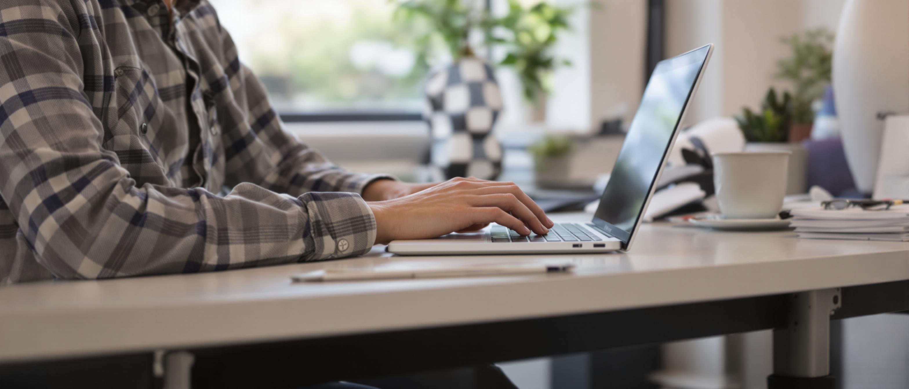 A person is sitting at a desk using a laptop.