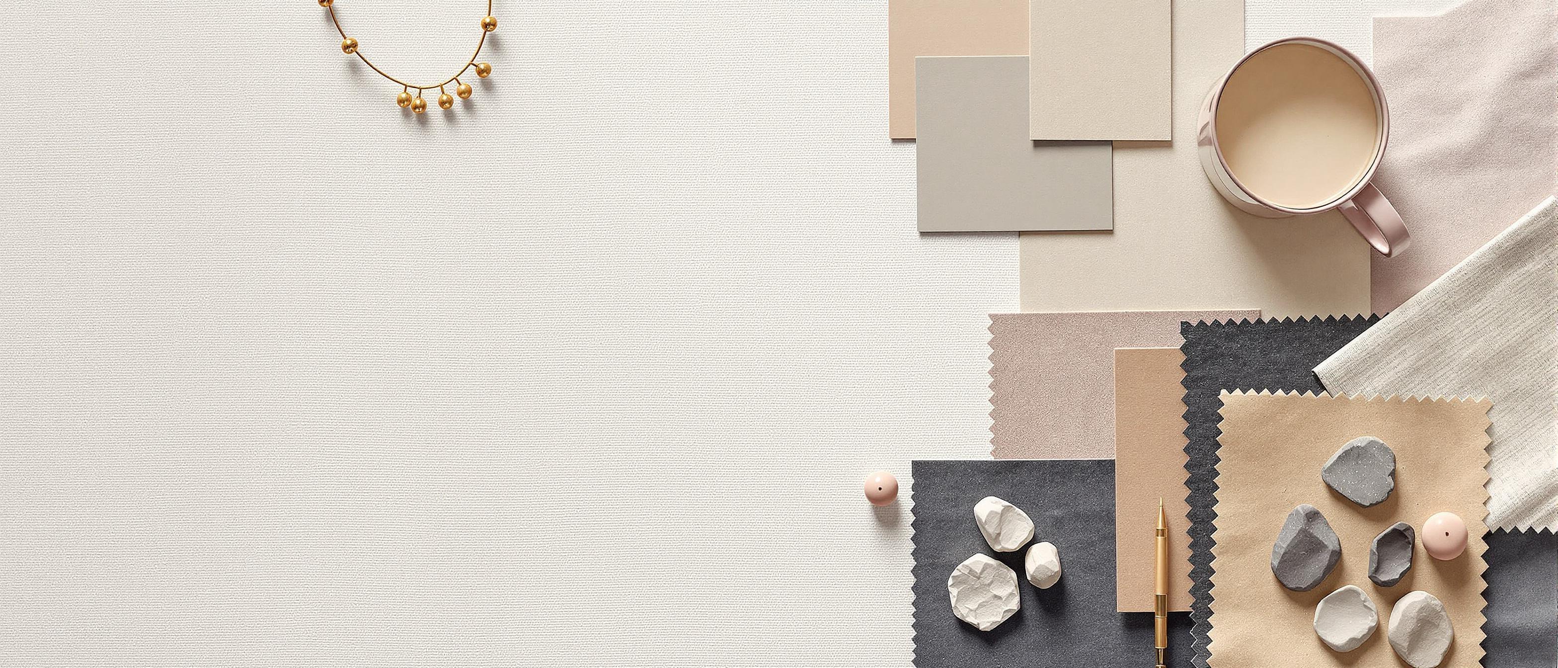 A curated arrangement of paint swatches, fabric samples, and textured papers displaying a harmonious color palette on a linen surface.
