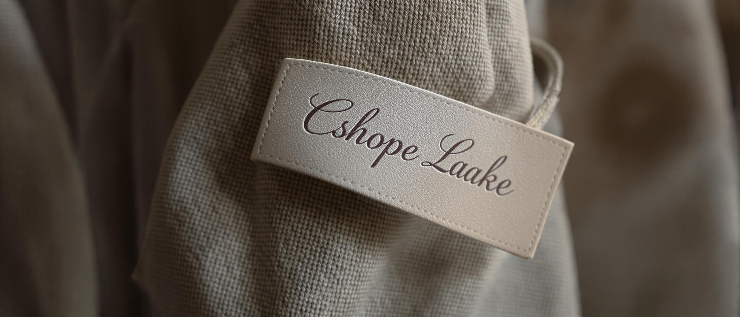 A close-up of a textured clothing tag with artistic font, softly lit and set against a blurred background.