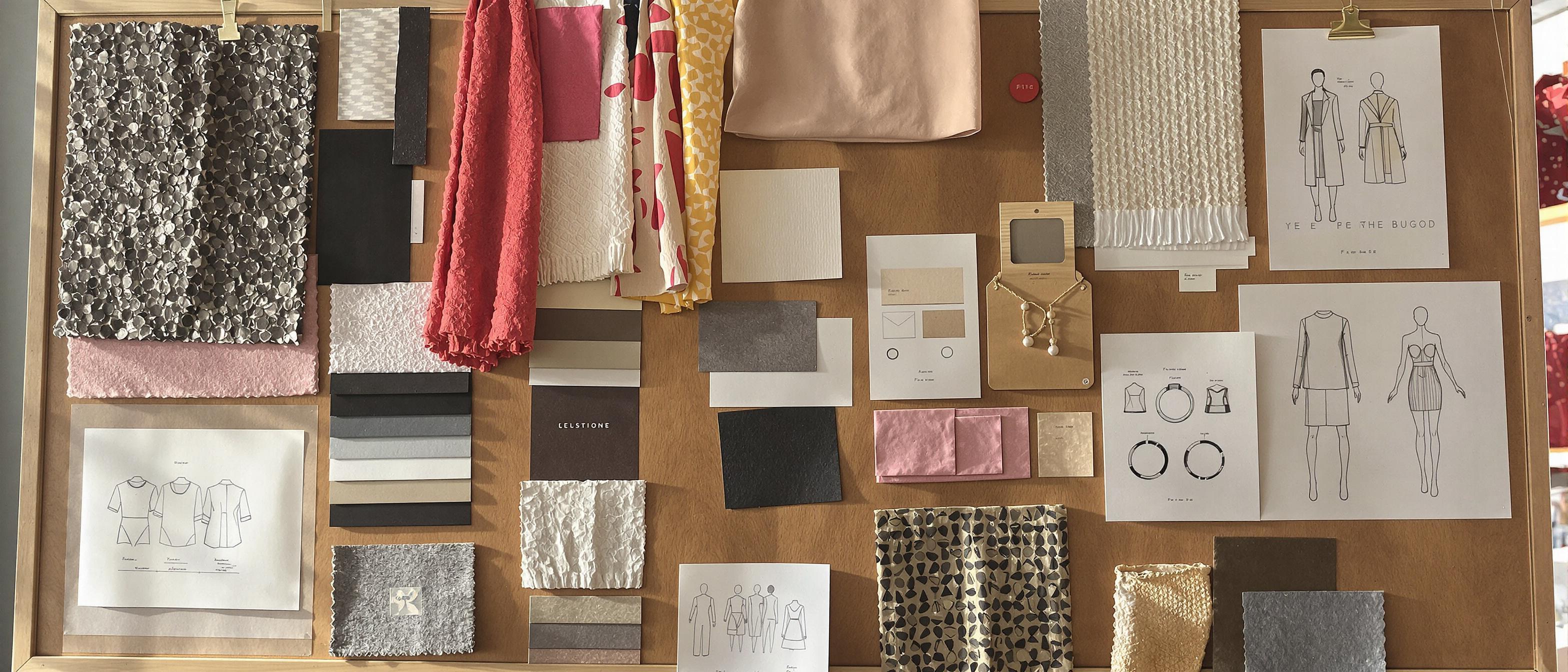 A curated collection of fabric samples and fashion design sketches displayed on a wooden board under natural lighting.