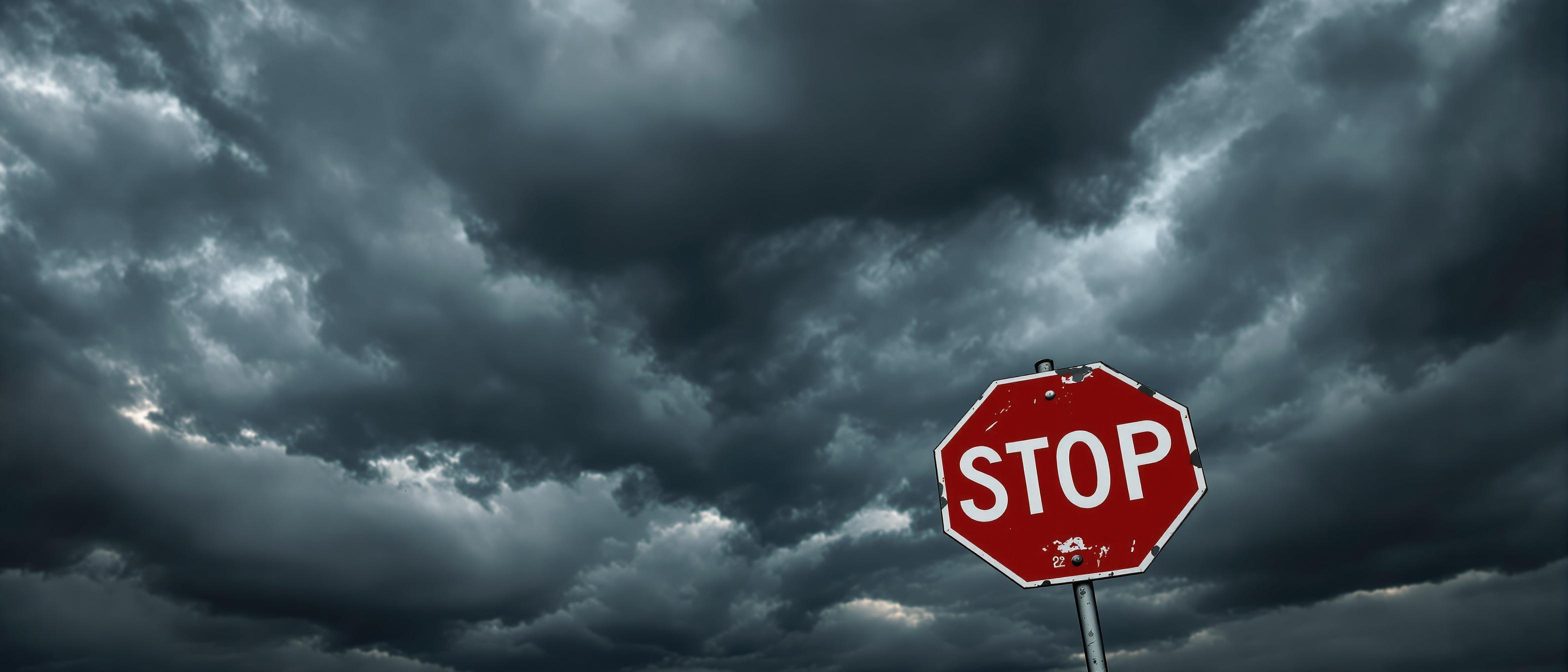 A classic red stop sign stands against a dramatic, stormy sky, evoking a sense of caution and foreboding.
