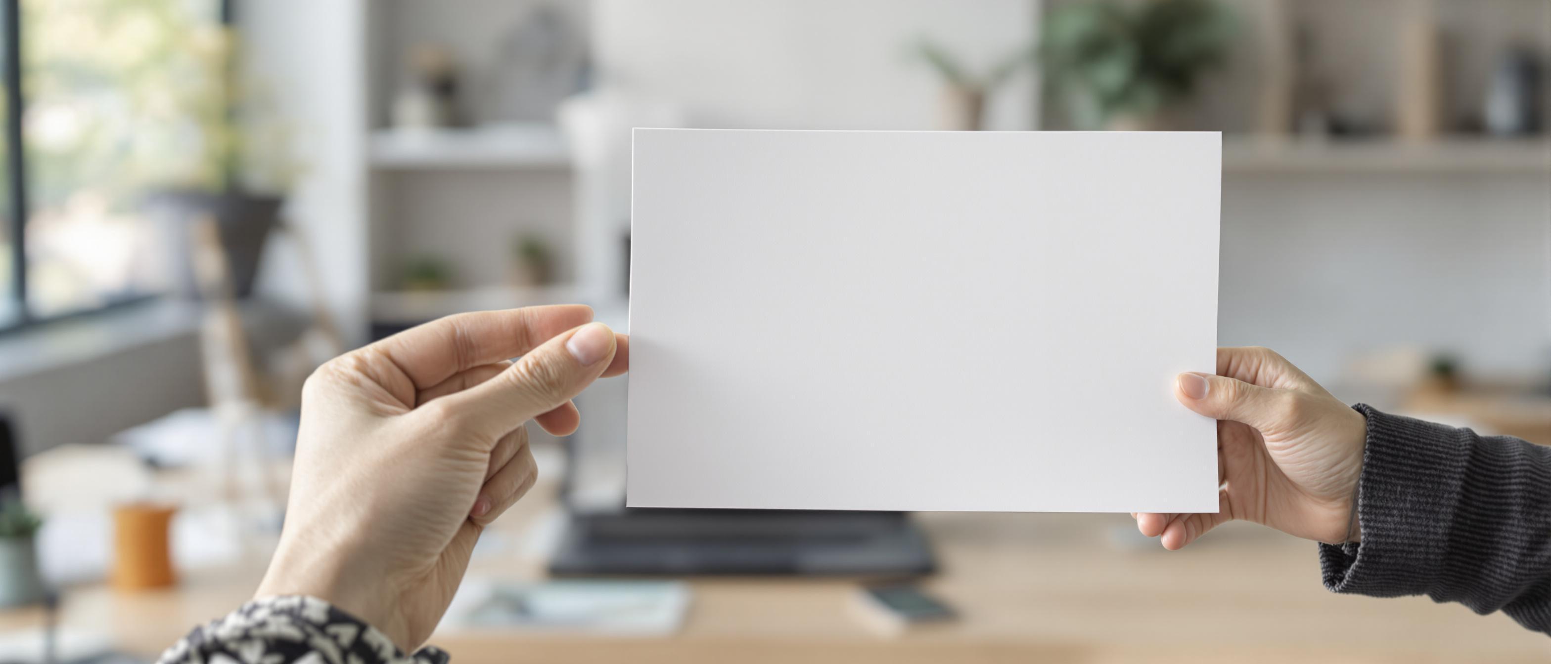 A person's hand gently holds a blank document, symbolizing business or legal agreements in a softly lit office setting.