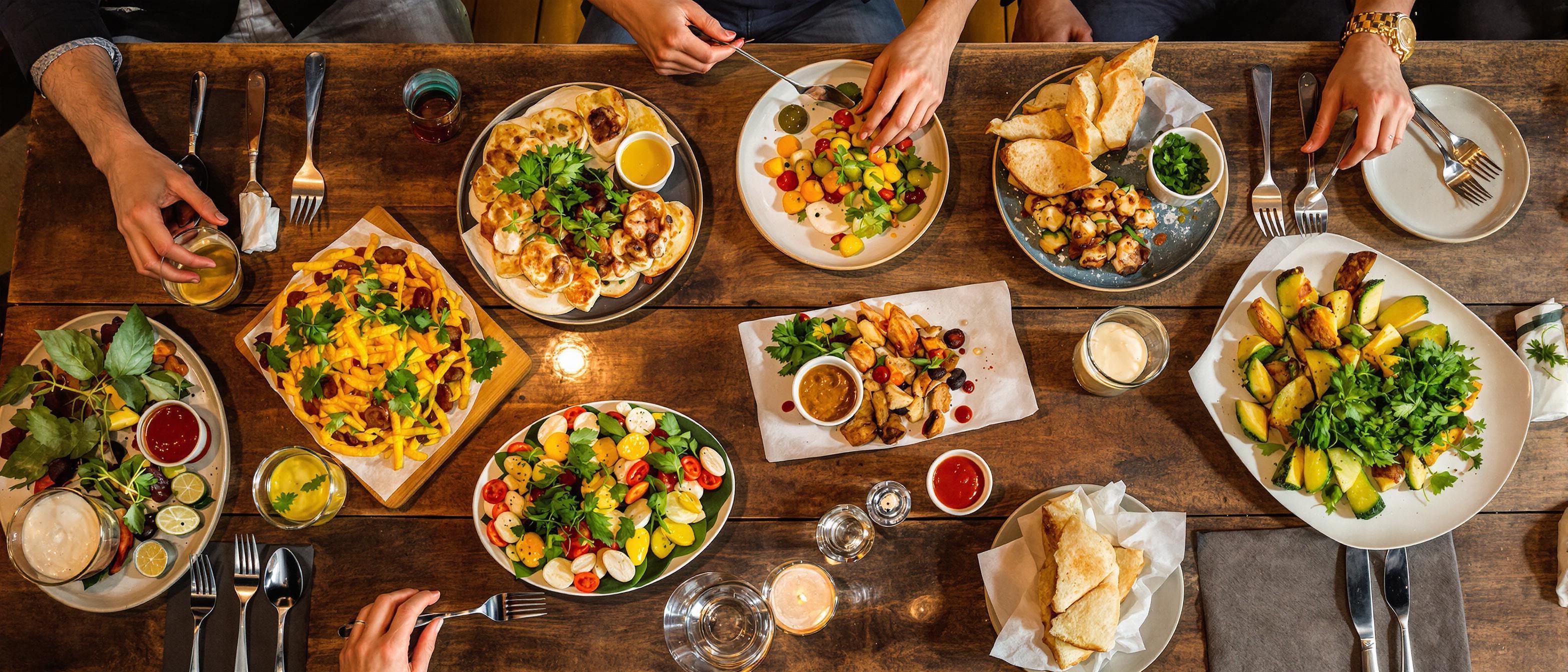 An array of appetizing dishes displayed on a wooden table in a warm, inviting restaurant setting.