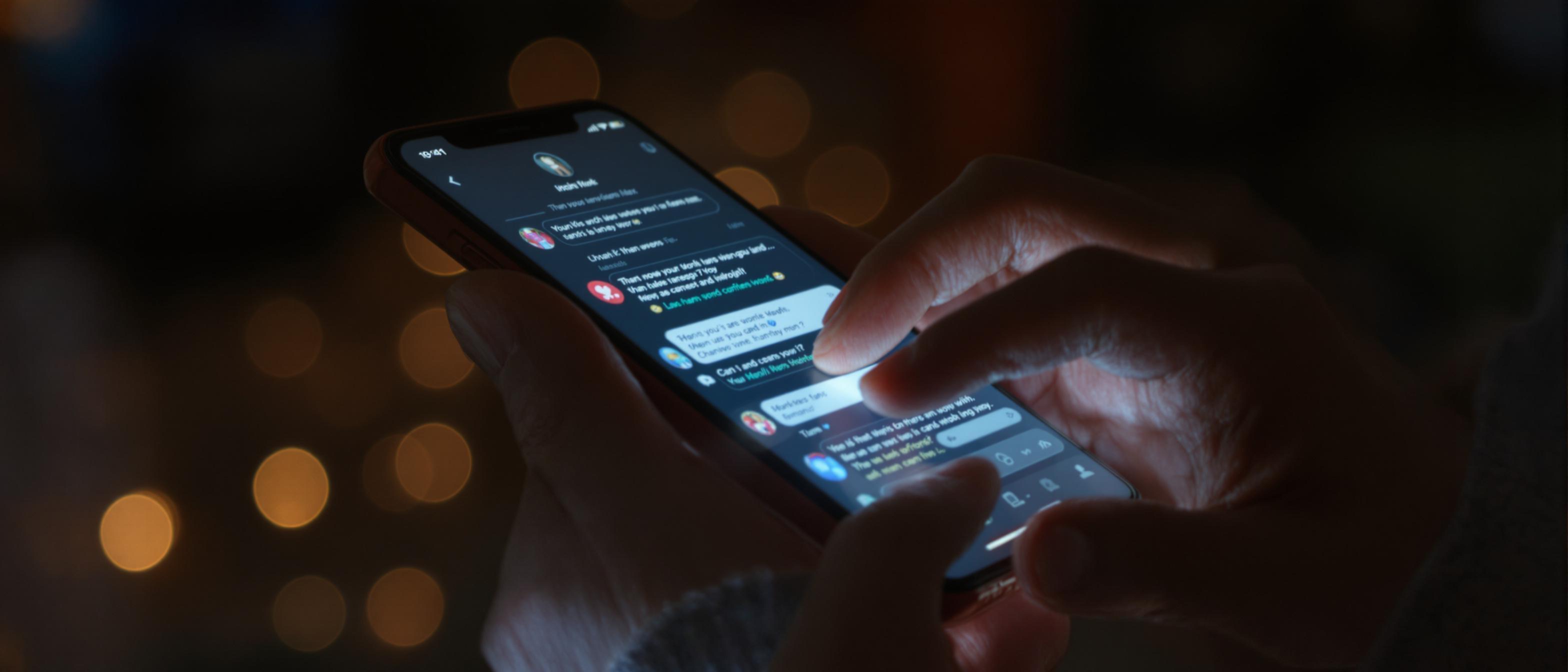 Close-up of hands using a smartphone displaying a social media feed with positive comments.